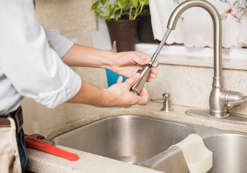 Plumber repairing a leaky kitchen faucet