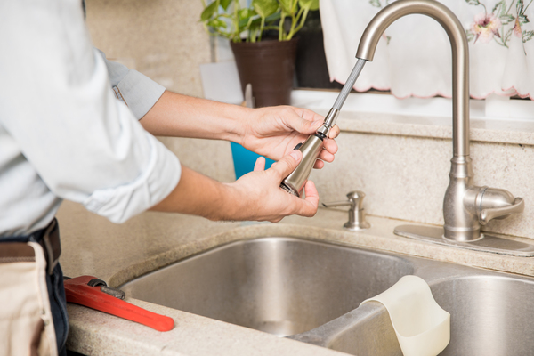 Plumber repairing a leaky kitchen faucet
