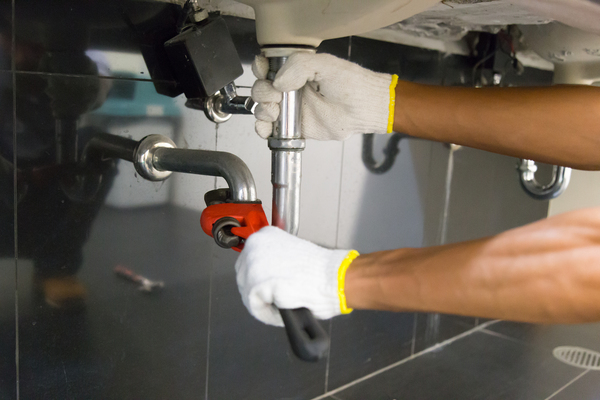 Plumber fixing a sink pipe with an adjustable wrench