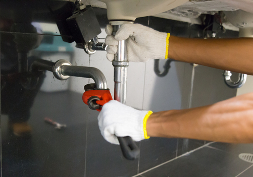 Plumber fixing a sink pipe with an adjustable wrench