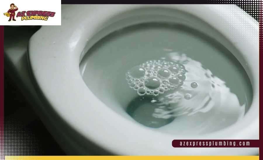 Air bubbles rising in a toilet bowl from a main drain clog