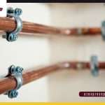 Flexible red and blue PEX plumbing pipes installed alongside rigid copper water supply lines