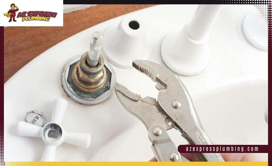 Close-up of locking pliers being used to repair a disassembled white bathroom sink faucet.